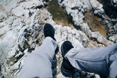 Low section of man sitting on rocky shore