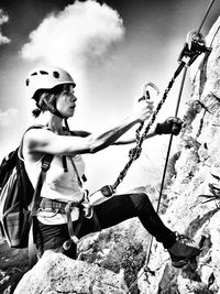 Low angle view of man holding rope against sky