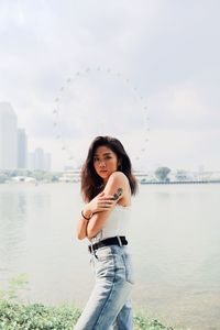 Portrait of beautiful young woman standing by sea in city