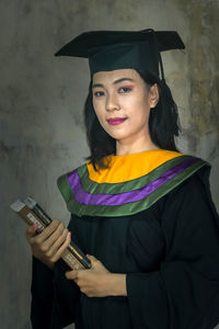 Portrait of a smiling young woman standing against wall