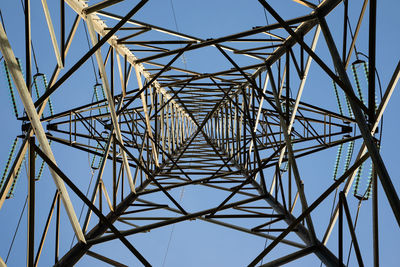 Low angle view of electricity pylon against clear blue sky