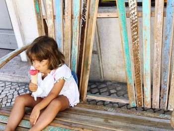 Girl holding baby sitting in front of building