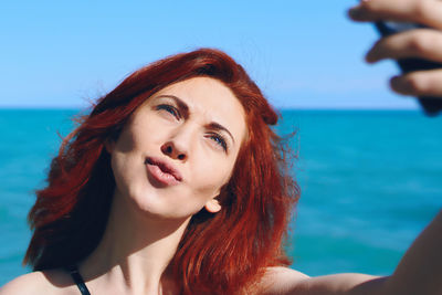 Portrait of beautiful woman against sea against sky