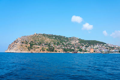 Scenic view of sea by townscape against sky