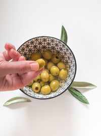 Close-up of hand holding fruit against white background