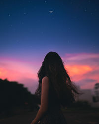 Rear view of woman standing against sky during sunset