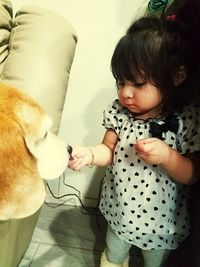 Close-up of cute girl playing with dog at home