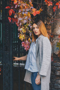 Portrait of smiling young woman standing by tree