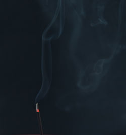 Close-up of emitting smoke against black background