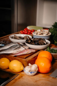 Sea bream, garlic, shrimp and shells on the table next to vegetables and fruit. 