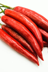 Close-up of red chili peppers over white background