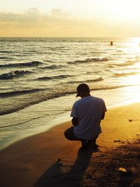 Rear view of man looking at sea during sunset