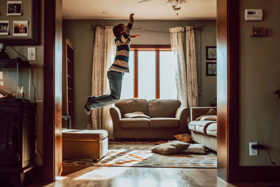 Woman jumping on sofa at home