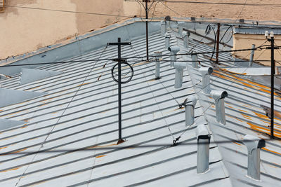 Photo of multiple ventilation pipes from stainless steel and antenna with wires on the rooftop