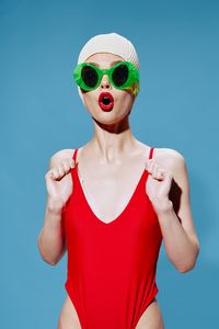 Portrait of young woman wearing mask against blue background