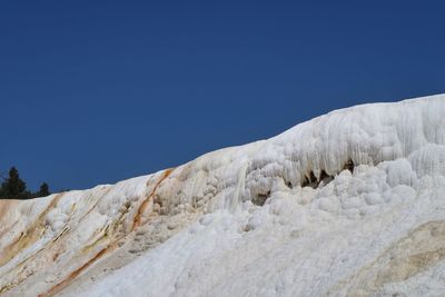 Low angle view of snow against clear blue sky