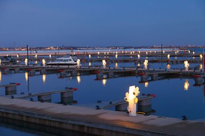 Illuminated bridge over sea against clear blue sky