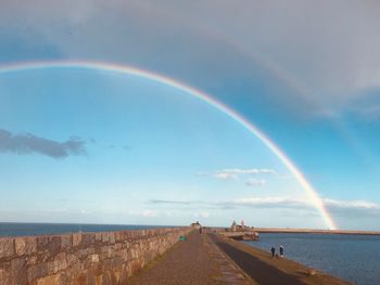 Scenic view of rainbow over sea against sky