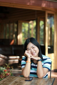 Portrait of smiling young woman sitting on table at restaurant