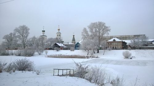 Church by snow covered field against sky