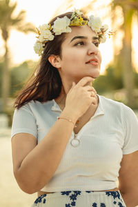 Young woman with arms raised standing against white wall