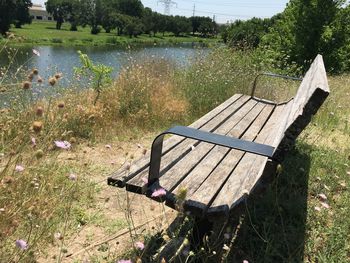 Empty bench on field by lake