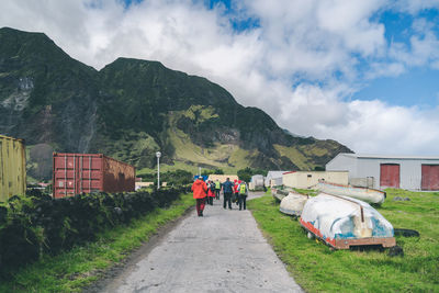 People on road by mountain against sky