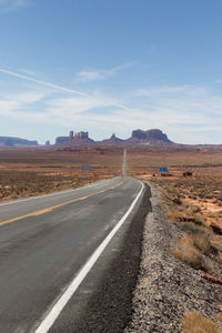 Empty road by landscape against sky