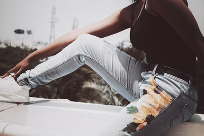 Midsection of woman holding umbrella while sitting outdoors