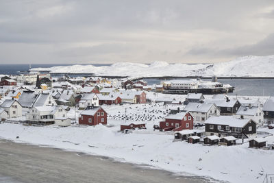 Houses by sea against sky during winter