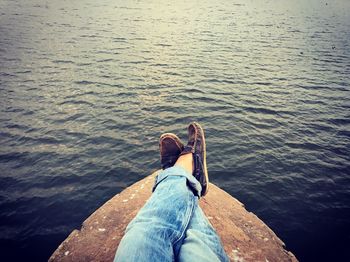 Cropped image of person relaxing on boat sailing over river