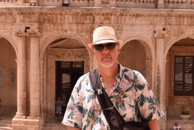 Portrait of senior man standing in front of building