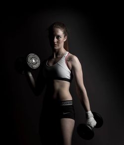 Young woman standing against black background