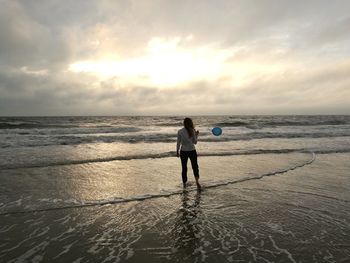 Rear view of man standing on beach against sky