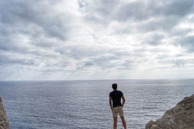 Rear view of man standing against sea at beach