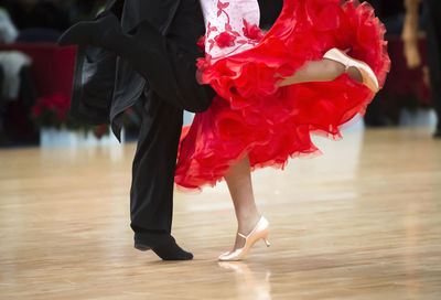 Low section of couple dancing on hardwood floor