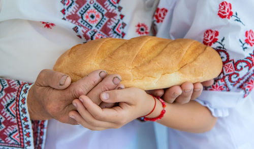 Hands of senior woman with girl holding bread