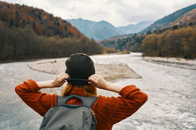 Rear view of man using mobile phone against mountains