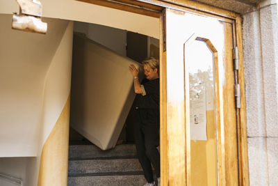 Woman carrying mattress at staircase