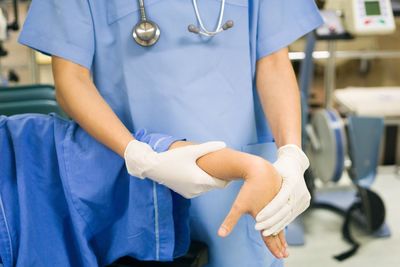 Midsection of doctor examining patient in hospital