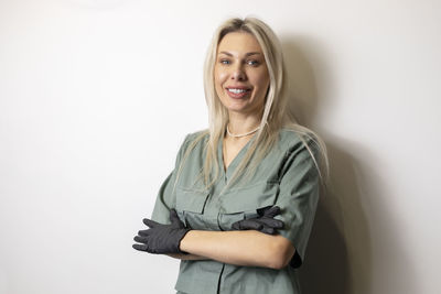 Portrait of young woman standing against wall