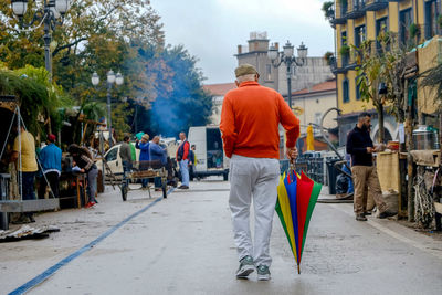 Rear view of people walking on street in city