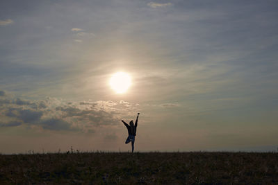 Silhouette man standing on field against sky during sunset