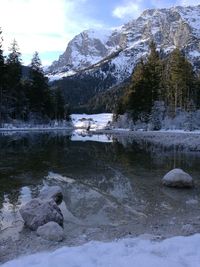 Scenic view of lake by snowcapped mountains against sky