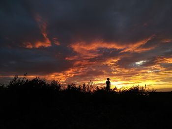 Silhouette of landscape against dramatic sky during sunset