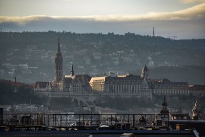 Buildings in city against cloudy sky