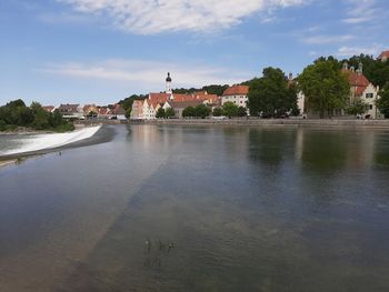 Scenic view of river by buildings against sky