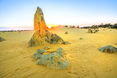 Scenic view of rocks on beach against clear sky