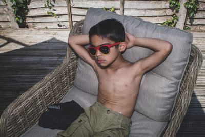 High angle view of young man wearing sunglasses sitting outdoors