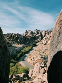 Man sitting on rock by mountains against sky